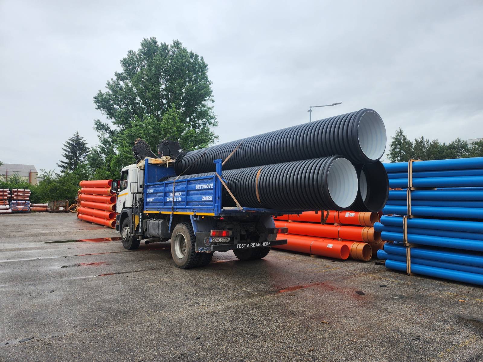 Nákladné auto preváža veľkoobjemové potrubia a stavebný materiál.